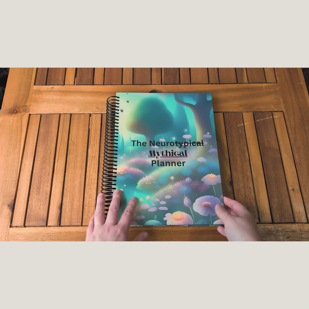 Overhead video of hands opening and flipping through the spiral-bound NeuroMythical planner.